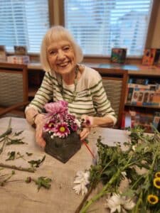 PCL Resident Marlene works on a flower bouquet for the Cypress Room.