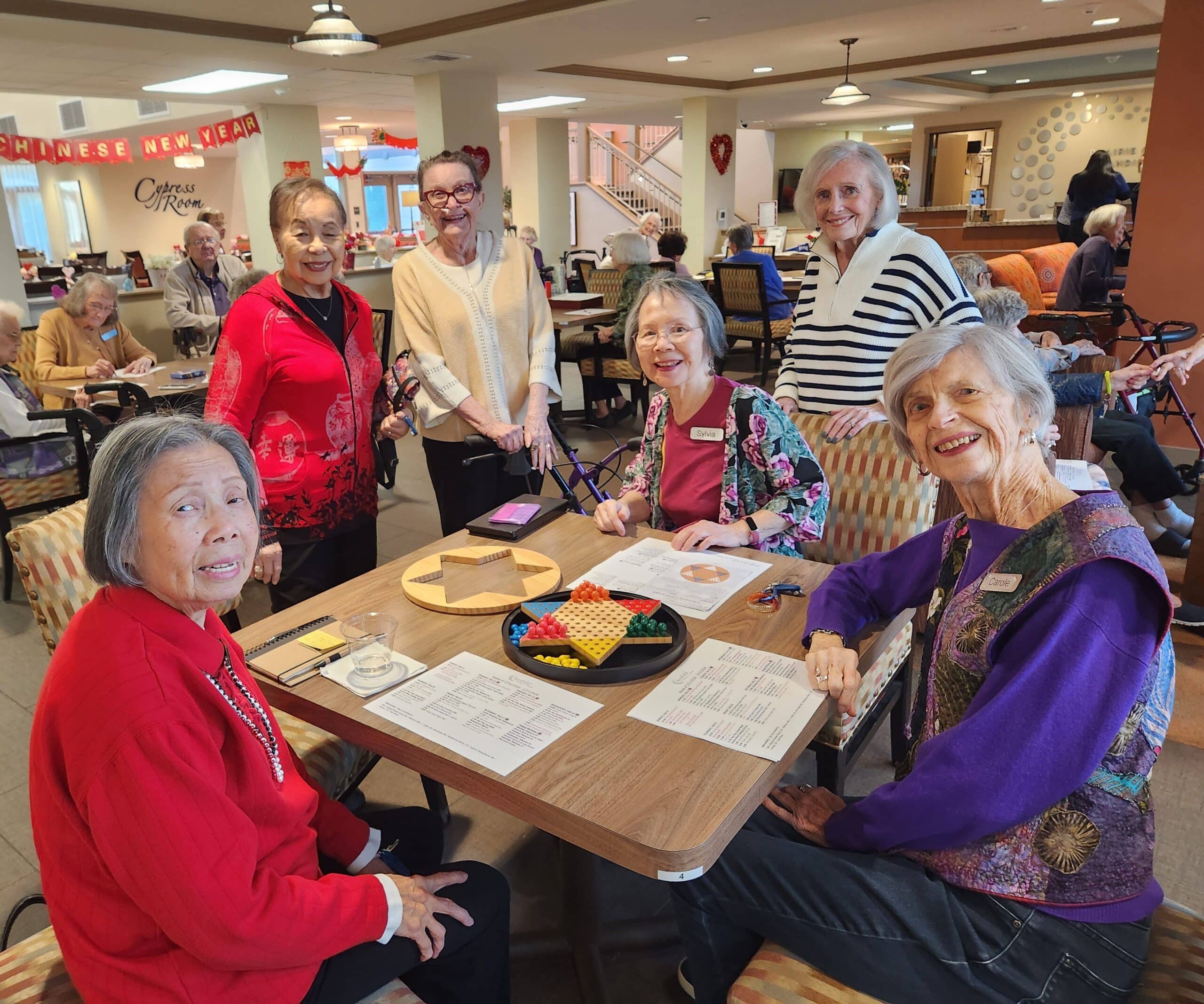 a group of 6 women gather around a table playing a game