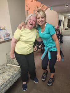 Two women stand laughing with each other in hallway