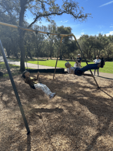 Two older women swing at park in sunny weather